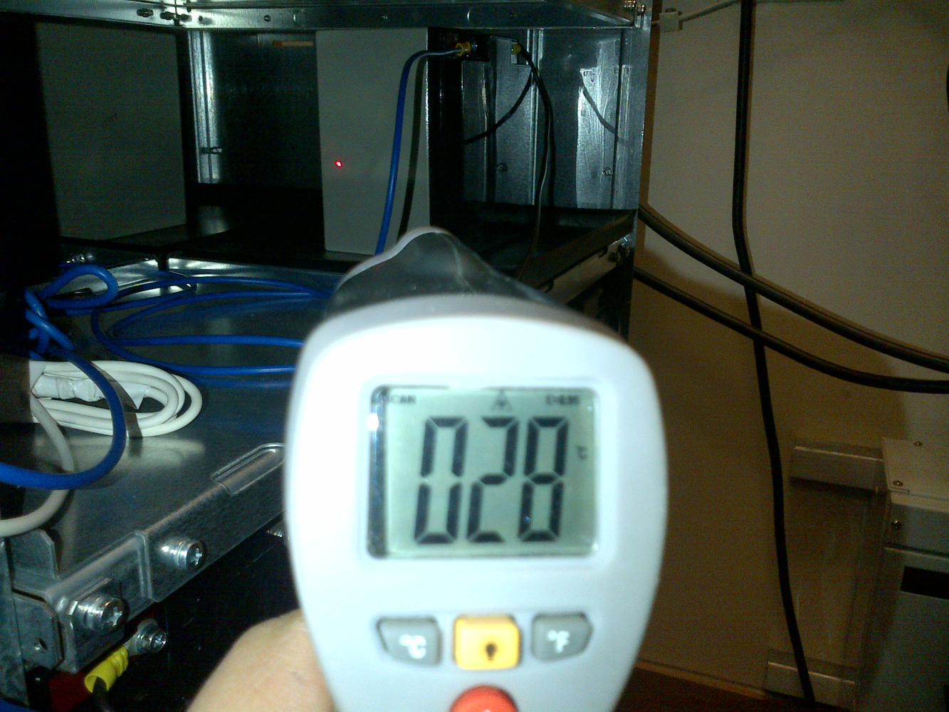 Handheld infrared thermometer in front of equipment internals