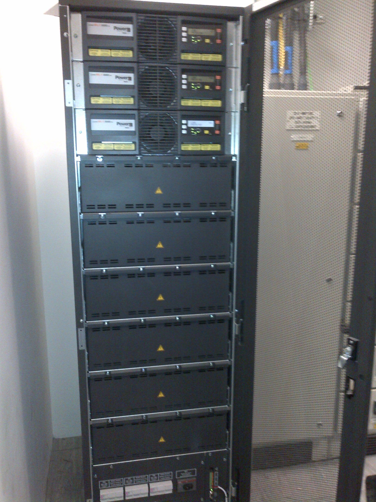 An open modular UPS cabinet showing power modules and lower equipment compartments.
